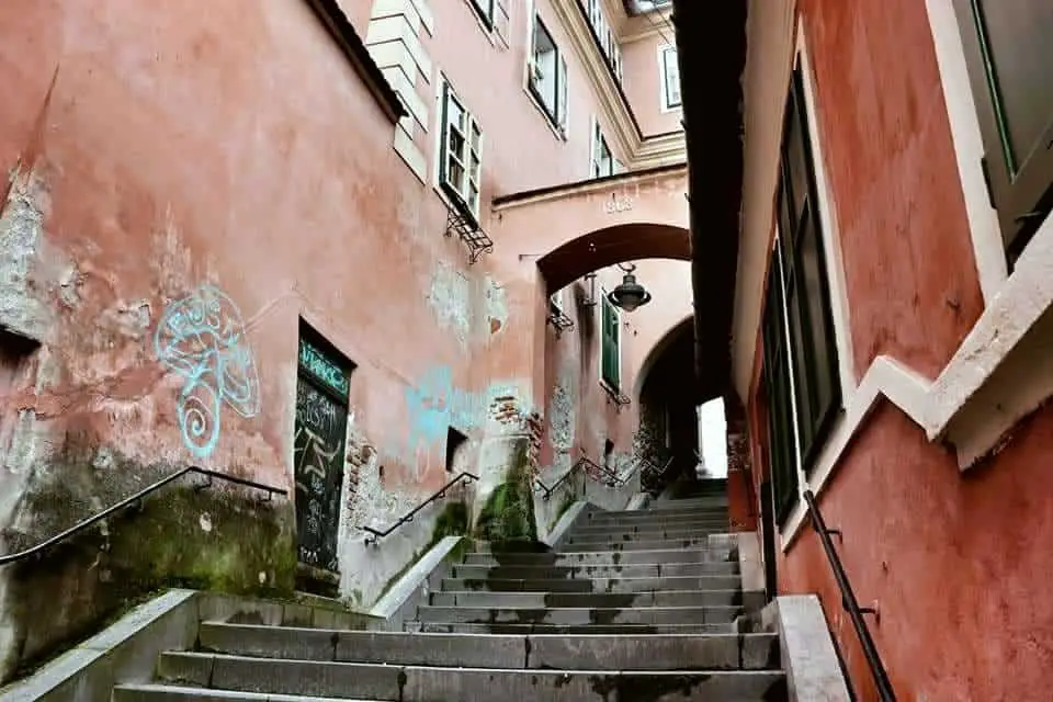 Pink walls line the Goldsmith's Stair Passage in Sibiu with a little graffiti on the left wall.