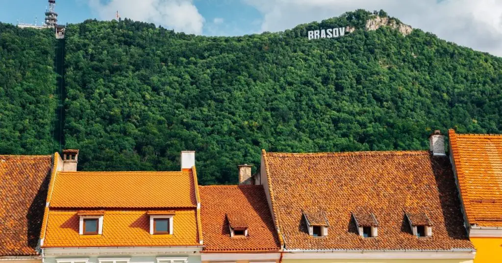 'Hollywood' Brasov sign seen in the trees on Tampa Mountain, Brasov with red roofs beneath the mountain.