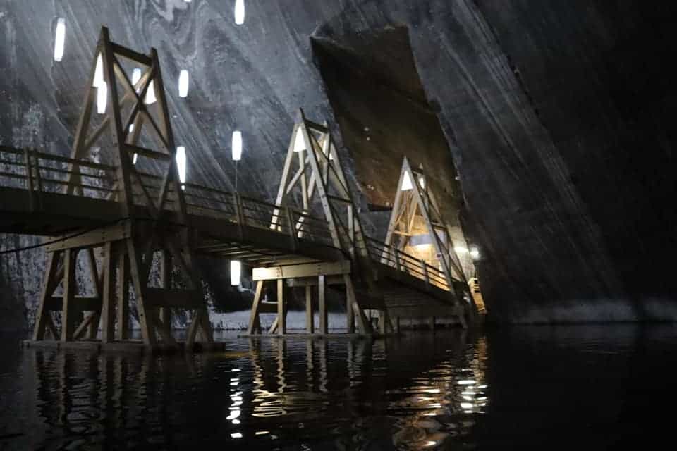 Lit up bridge spanning an underwater lake at Turda Salt Mine.