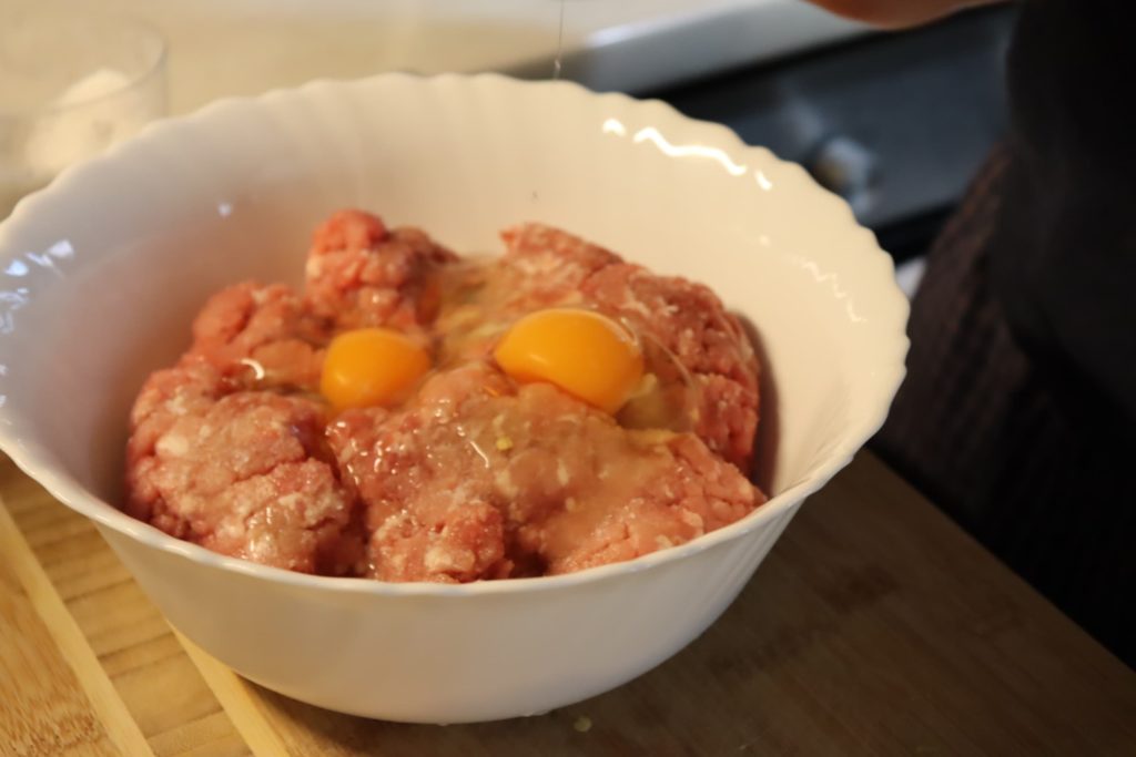 two eggs in a bowl of ground meat