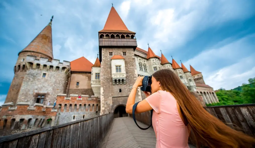 Woman taking picture of Corvin Castle with interesting angle - Transylvania, Romania.
