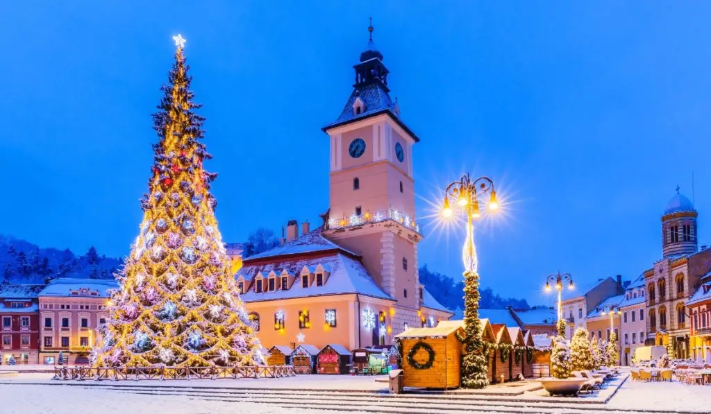 Brasov Christmas Market covered in snow and lights at dusk.