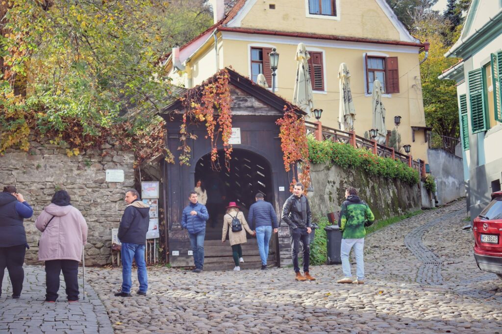 Entrance to the covered staircase in Sighisoara with people standing around in coats and jackets.