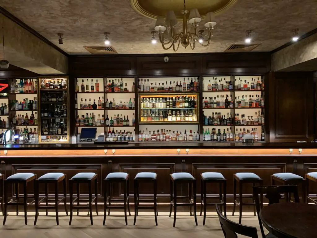 Dark and moody bar with line of backless bar stools in Cluj-Napoca.