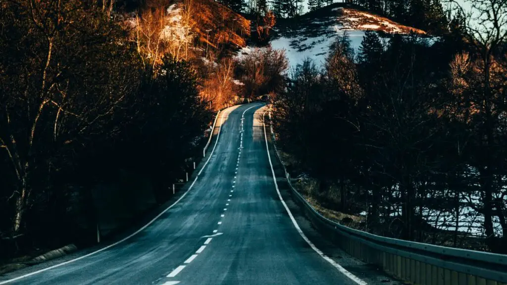 Romanian mountain road at sunrise with snow in the background