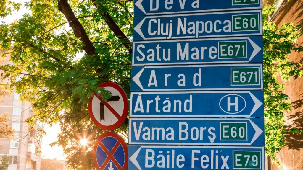 Street sign in Romania depicting different cities and their distances.