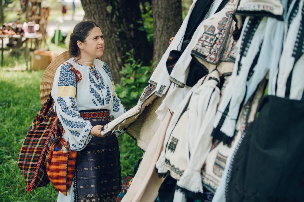 Woman in traditional Romanian clothes hanging textiles at Sibiu Astra Museum.