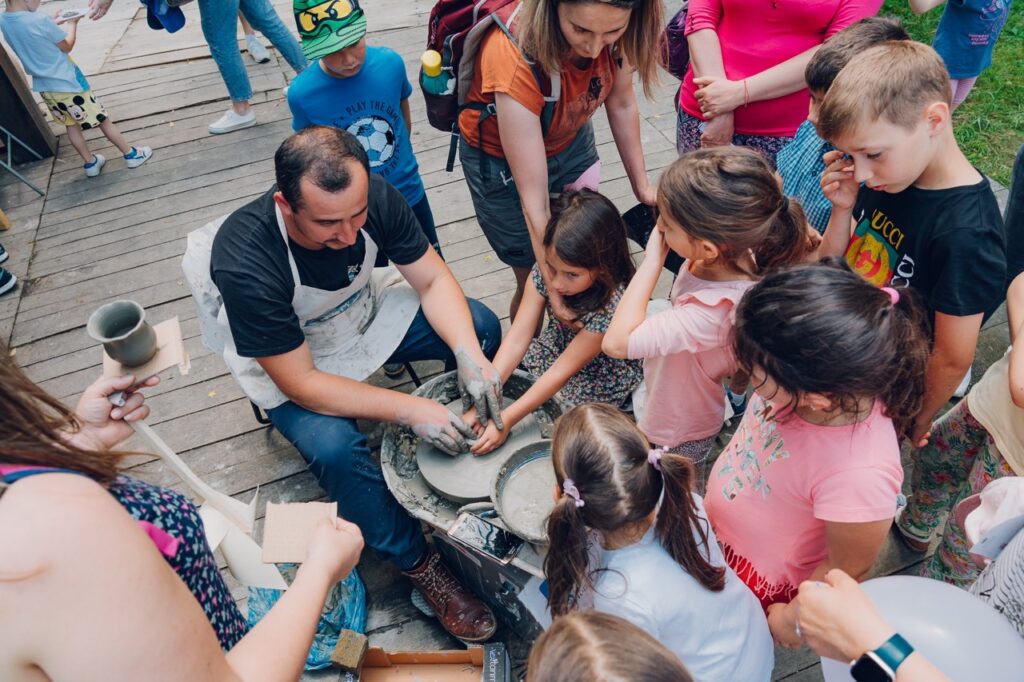 Kids gathering around a pottery demonstration at Astra Sibiu.