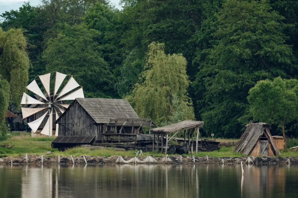 Windmill and old buildings next to a lake at Sibiu Astra Park