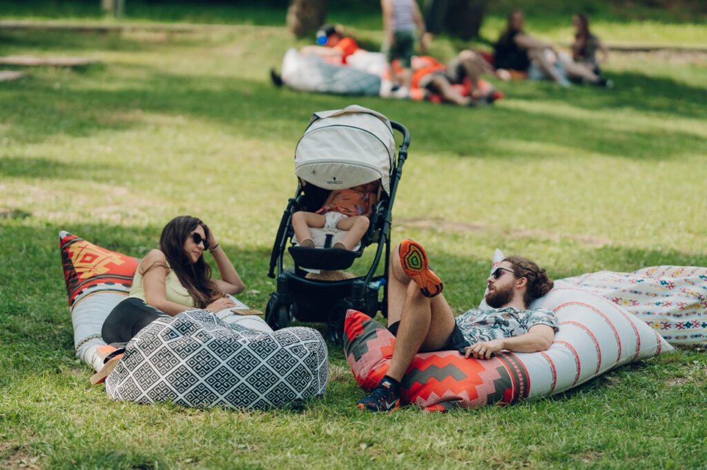 Couple with baby in stroller relaxing in the grass at Astra Museum complex Sibiu.