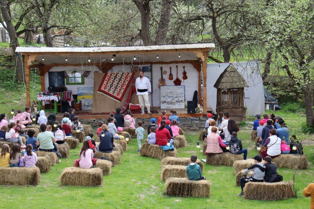 Many kids seated on hay bales in breb at a puppet show