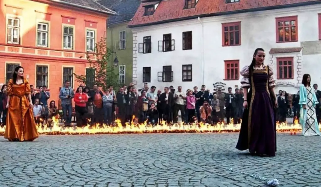 Medieval performance in Sighisoara with fire along the ground and women in costumes.
