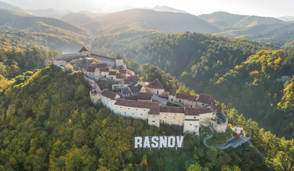 Rasnov Fortress surrounded by hilly forests.