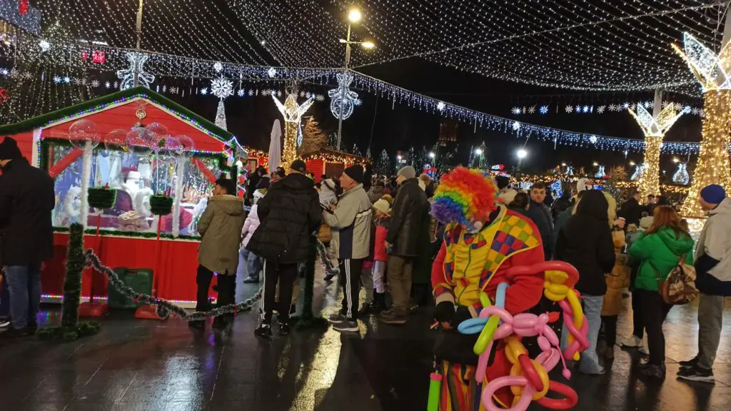 Craiova Christmas Market at night, clown with balloon animals in the foreground.